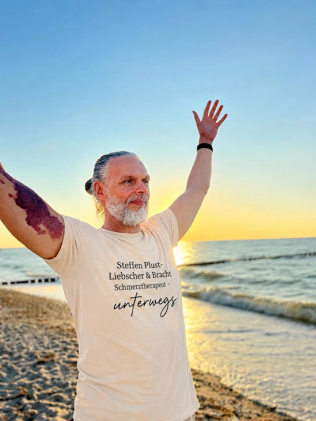 Steffen Plust zeigt eine freie Schulterbewegung am Meer